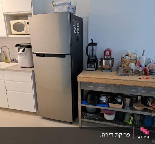 מטבח מאורגן עם מקרר, מיקרוגל וכלי מטבח על מדף